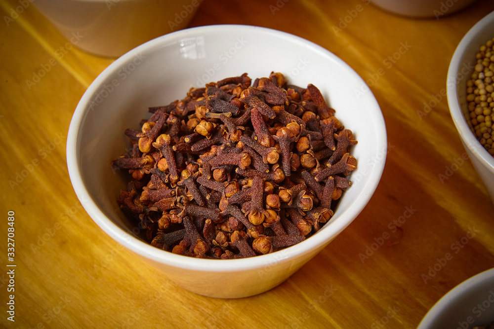 cloves in white bowl on wooden background cloves in white bowl on wooden background