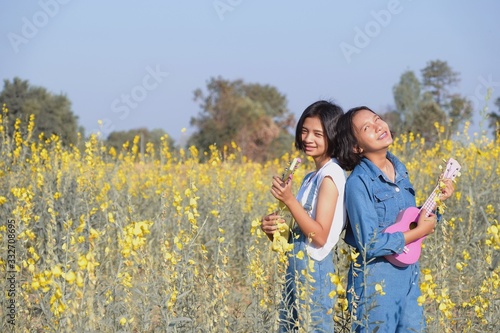 Happy ASian yoing girl play ukulele at flower field. photo