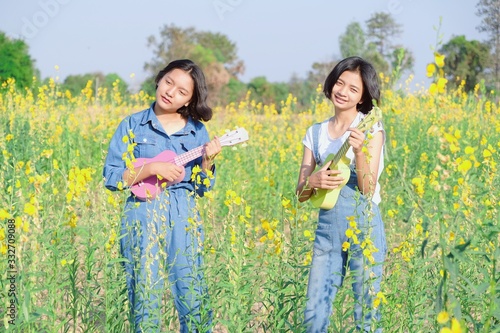 Happy ASian yoing girl play ukulele at flower field. photo