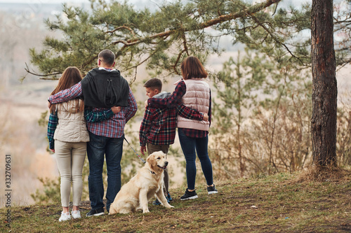 Rear view of family that standing together with their dog outdoors in forest