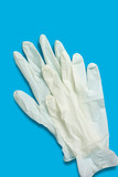 Two light hygiene gloves on a blue background. Top view. Vertical orientation