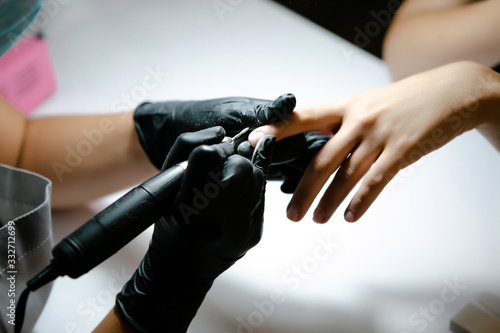 Woman use electric nail file drill in beauty salon.