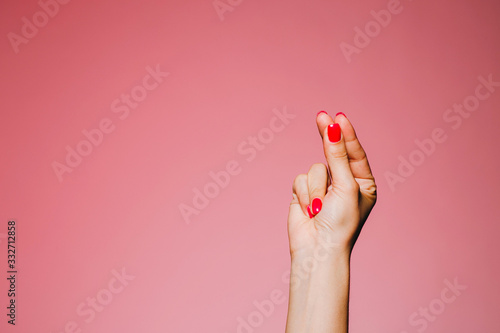 Woman's snapping hand with bright manicure isolated on pink background