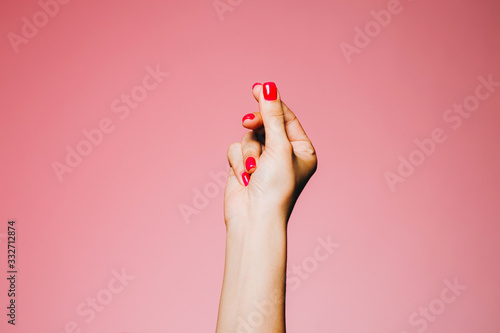 Woman's snapping hand with bright manicure isolated on pink background