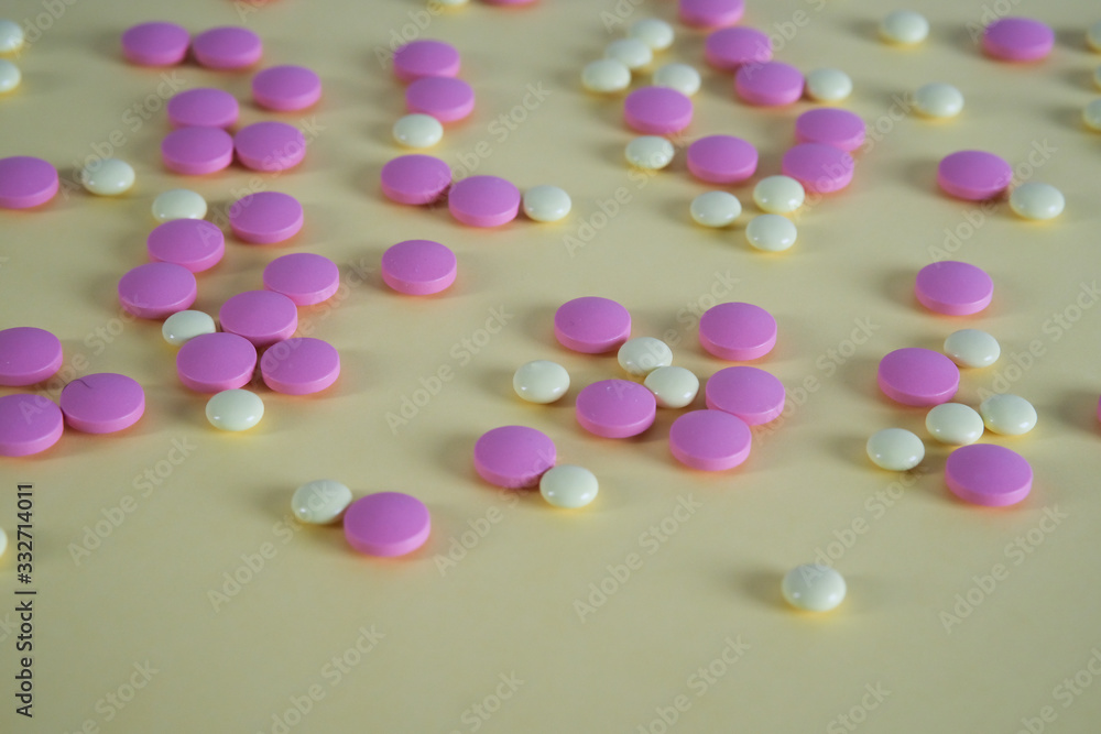 Multicolored round medical tablets on a yellow background. Space for text