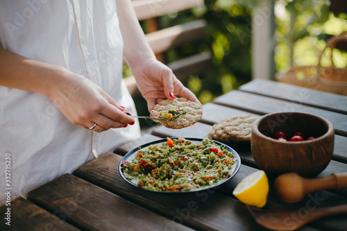 Woman's hands putting guacamole on a toast with a fork. Summer picnic with Mexican food