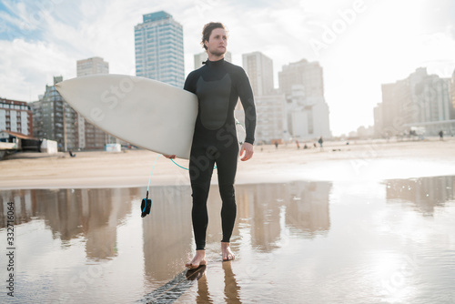Surfer standing in the ocean with his surfboard.
