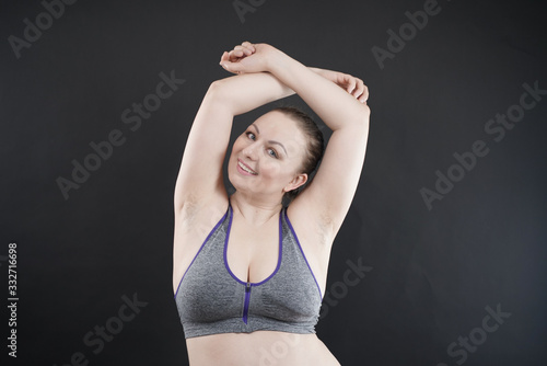 young happy plus size caucasian woman shows her unshaved armpit