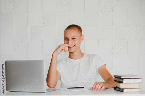 Young smiling student sitting at laptop and studying. Isolated on white.