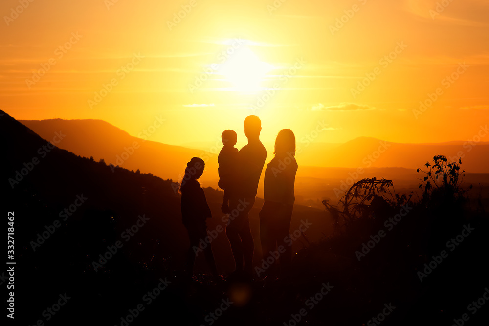 Family's silhouette at sunset with father, mother, son and daughter