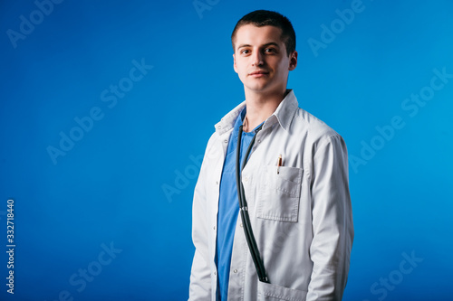 Portrait of young doctor with stethoscope isolated on blue background