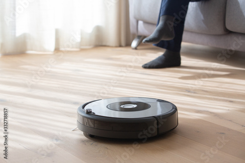 Fotografie robot vacuum cleaner cleaning a living room