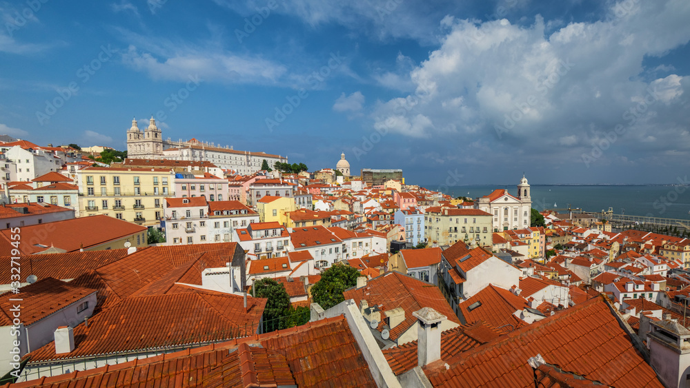 A big panorama of lisbon from a terrace. All the rooftops from above and the monastery of vincent and the santo estvao chruch at the back.