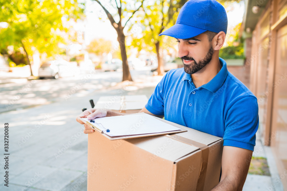 Delivery man carrying package outdoors. Delivery man carrying package outdoors.