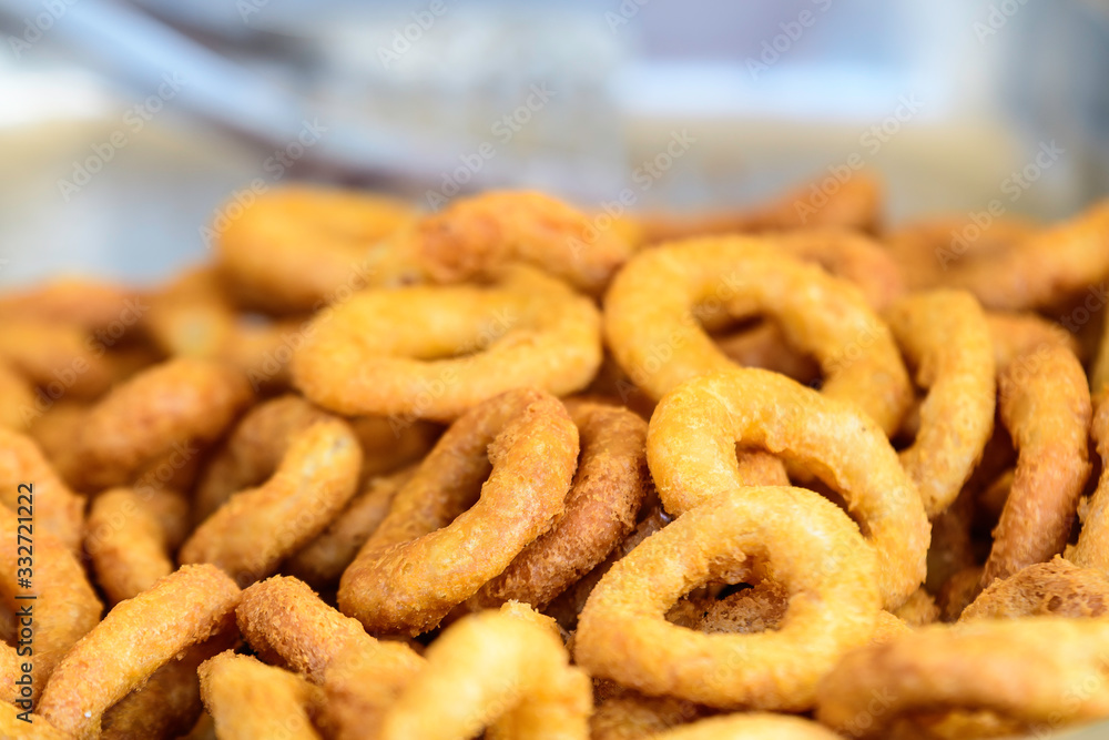Large group of freshly fried calamari and onion rings on display for sale at a street food festival, ready to eat healthy seafood, beautiful orange monochrome outdoor background Large group of freshly fried calamari and onion rings on display for sale at a street food festival, ready to eat healthy seafood, beautiful orange monochrome outdoor background