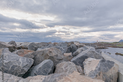 Lighthouse on the Lofoten Islands. Travel to Norway. Norwegian fjords. Huge blocks of stones in the foreground. Photo taken at midnight, midnight sun