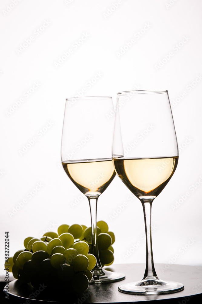Two glasses with white wine and grapes on white background Two glasses with white wine and grapes on white background