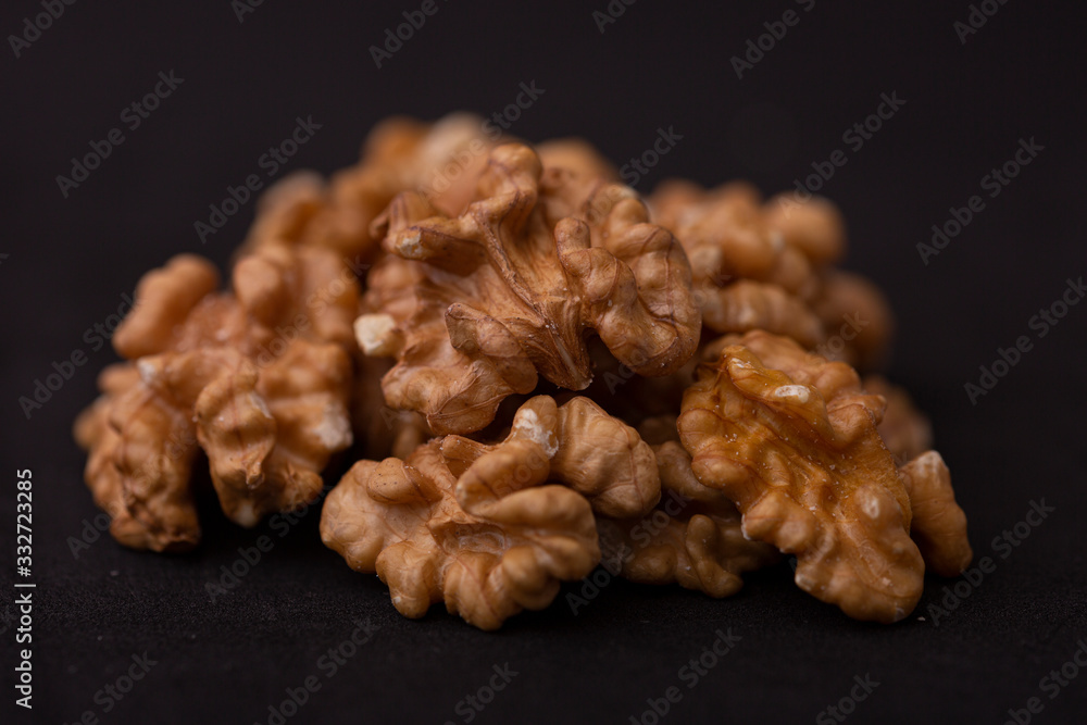 Closeup macro low key still life of vibrant brown walnut nuts contrasted against a dark studio background