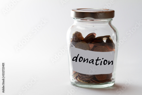 bulbous jar with screw cap filled with coins and the word donation on a label photo