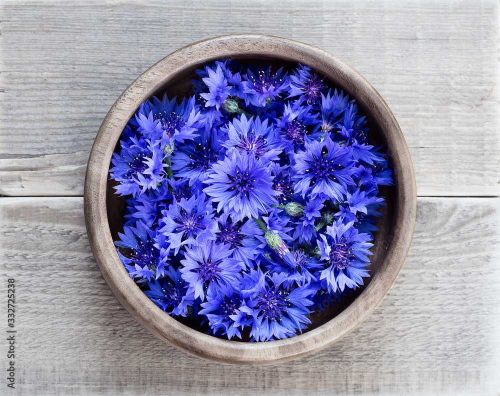 Cornflowers in a wooden bowl on a wooden table. Flowers Cornflowers collected for drying. Herbal tea cornflower buds