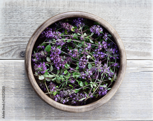 Thyme in a wooden bowl on a wooden table. Flowers thyme collected for drying. Herbal tea thyme. Top view