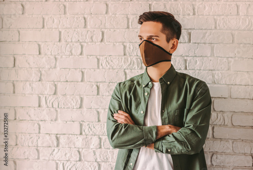 Confident young man in stylish shirt in respirator or face mask. Professional pesonal protection from air pollution, coronavirus nCov-19. Hipster student wearing protective face mask against COVID-19 photo
