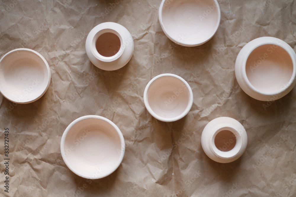 dishes made of white clay without glaze after firing on a brown background close-up. pottery top view dishes made of white clay without glaze after firing on a brown background close-up. pottery top view