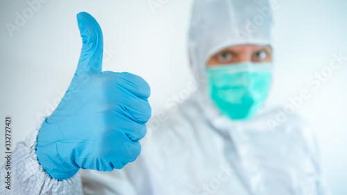 Male caucasian doctor wearing a protective suit and mask making Yes sign gesture