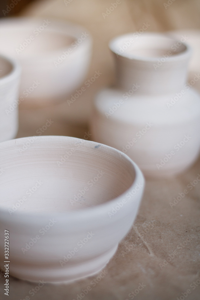 dishes made of white clay without glaze after firing on a brown background close-up. pottery dishes made of white clay without glaze after firing on a brown background close-up. pottery