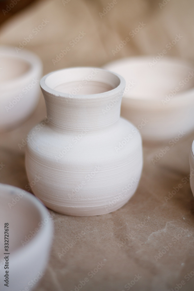 dishes made of white clay without glaze after firing on a brown background close-up. pottery dishes made of white clay without glaze after firing on a brown background close-up. pottery