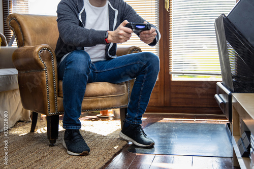 Young man sitting on a couch playing video games in a rustic house. Gamer concept