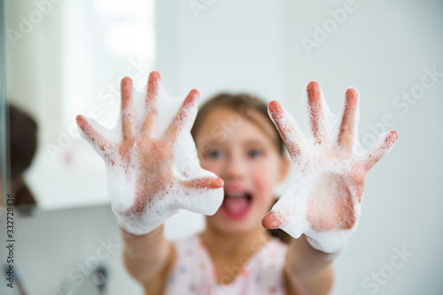 Little girl washing hands with water and soap in bathroom. Hands hygiene and virus infections prevention. 