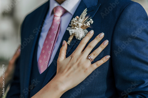 Bride's hand and rings on groom's blue outfit