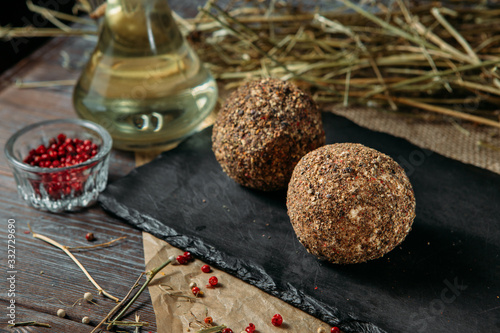 Close-up of two mozzarella balls in oil with different spices on a black wooden board on a rustick background. photo