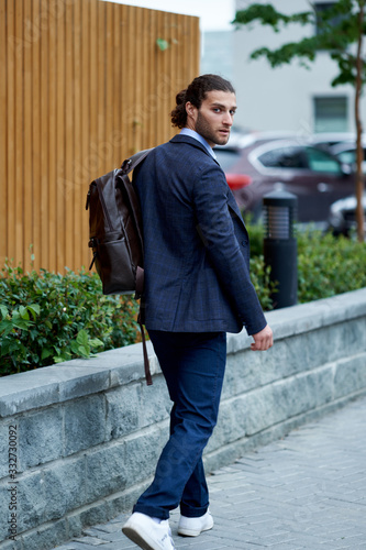 Attractive bearded young man in classic suit with backpack. Elegancy and male style