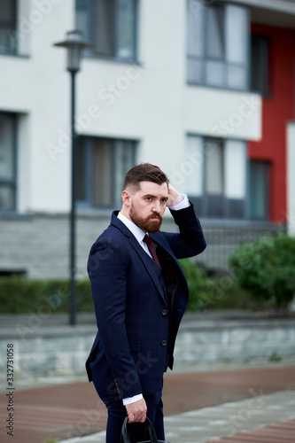 Attractive bearded young man in classic suit with bag. Elegancy and male style