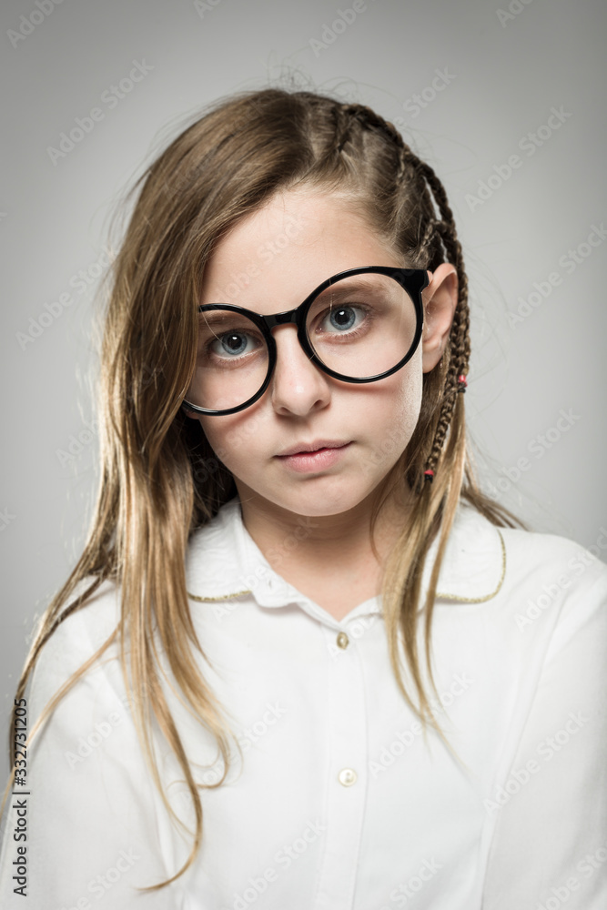 Studio portrait of a cute girl with long blonde hair wearing glasses against neutral background Studio portrait of a cute girl with long blonde hair wearing glasses against neutral background
