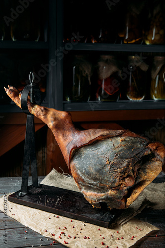 Spanish delicatess smoked pork leg for slicing on a holder, on rustic background. photo