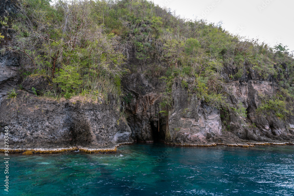 Bat Cave in St. Martinique Island in the Caribbean. Beautiful blue water surrounding cave entrance 