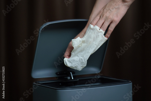 Hand putting used dirty surgical glove to  a garbage bin. Mask protect dust and corona virus in trash.