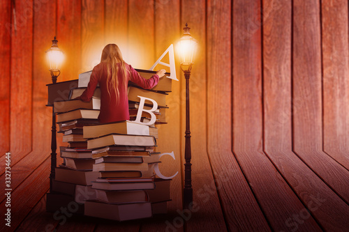 Pile of Books with Student and Lit Lamps on Wooden Background