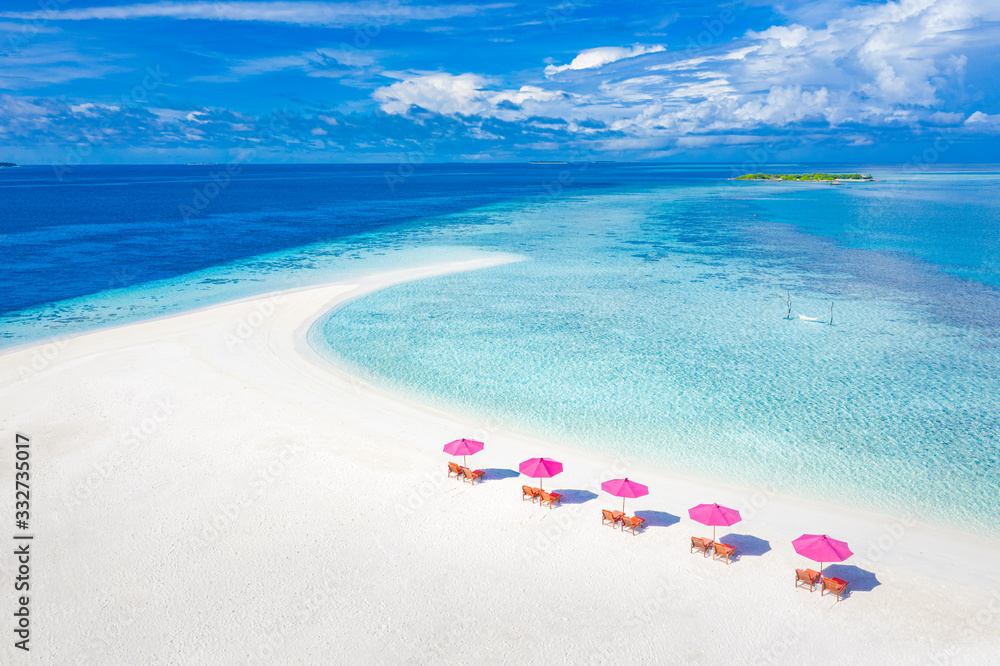 Luxury aerial beach vacation, summer travel and holidays. Loungers, chairs with pink umbrella close to blue sea. Tropical island paradise view, aerial nature landscape