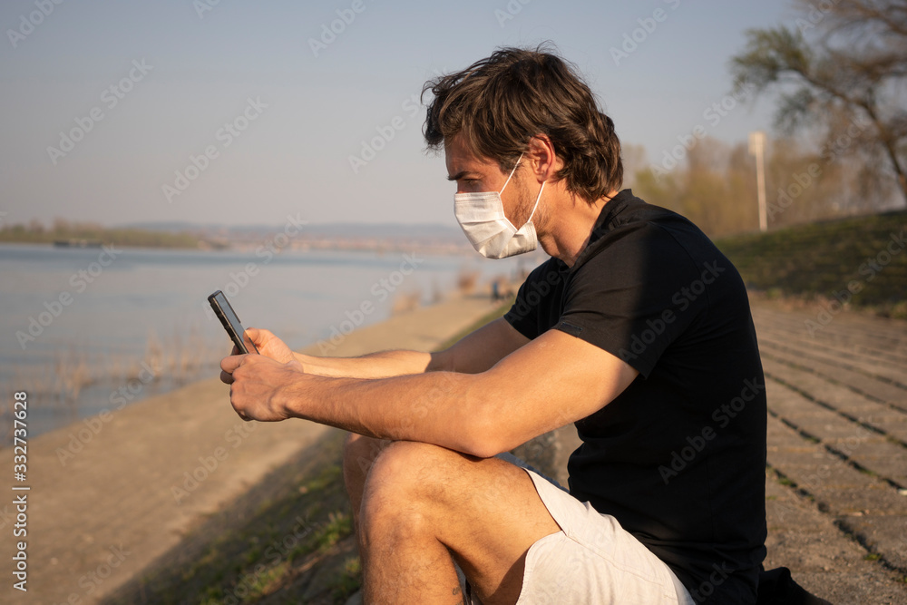 Man wears mask to prevent virus and for protection while using mobile phone