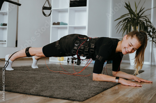 Young woman in EMS training suit with cables doing plank.