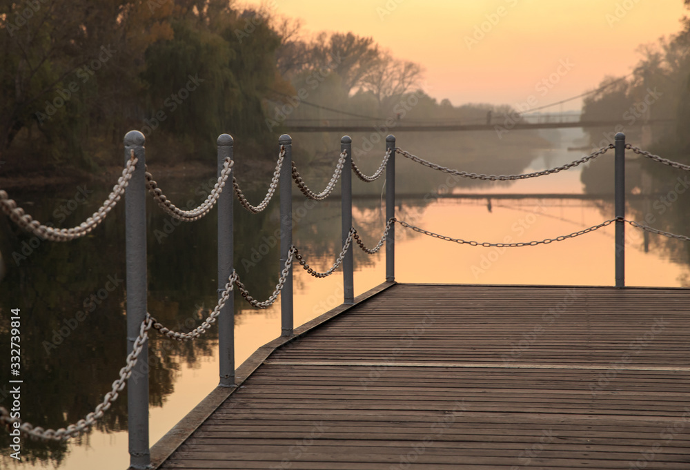 Fototapeta premium Pier by the river during sunset. Chain fence
