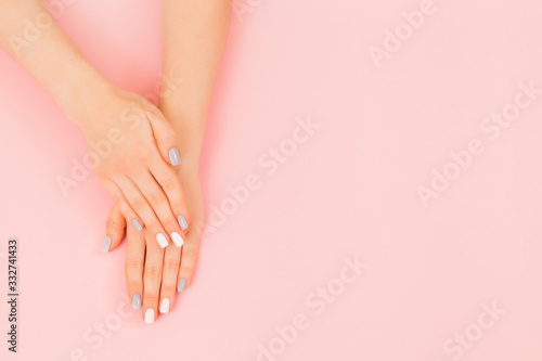 Stylish trendy female manicure. Beautiful young woman s hand with perfect grey manicure on pink background. Flat lay style.