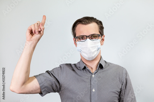 Infected Caucasian man with perfect calm gesturing with forefinger, pointing with finger upward, grey background