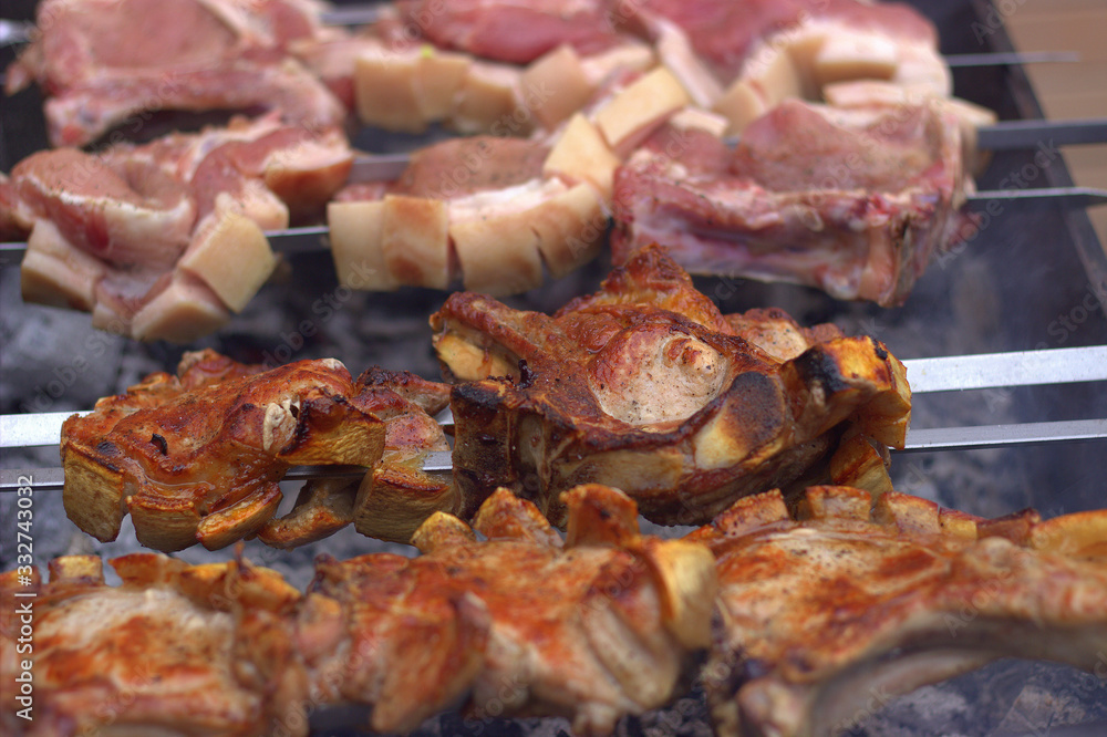  Raw and cooked pork entrecotes with a layer of grilled fat. Smoke comes from hot coals
