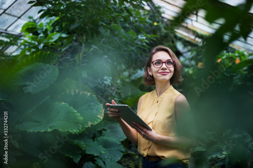 Young woman with tablet standing in botanical garden. Copy space. photo