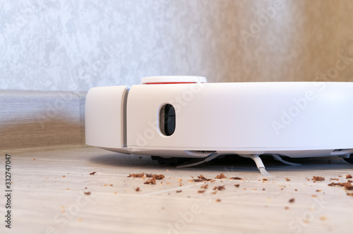 Robotic vacuum cleaner removes breadcrumbs from the laminate wood floor.
